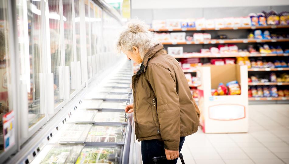 Mujer revisa la sección de congelados de un supermercado.