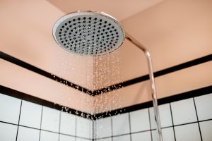 Noticias 29 Chorro de agua cayendo de una ducha encendida, ilustrando el momento perfecto para disfrutar de la temperatura ideal del agua para ducharse.