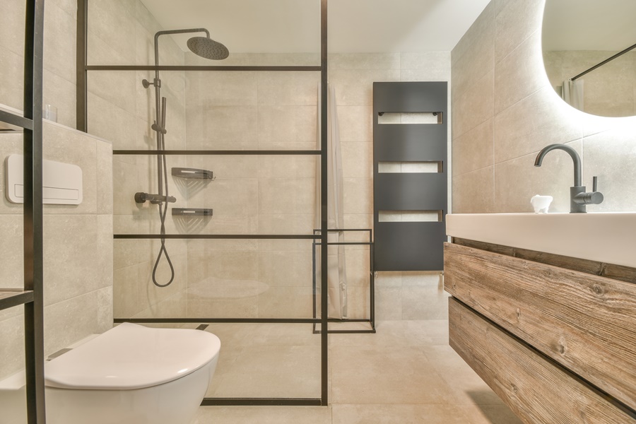Columna de ducha contemporánea en un baño de estilo minimalista con mampara de metal negro, muebles de madera y espejo con luz LED integrada.