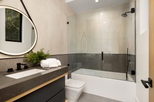 Noticias 22 Baño moderno con bañera equipada con mampara de cristal corredera, ideal para ilustrar cómo elegir la mampara de ducha perfecta en espacios pequeños.