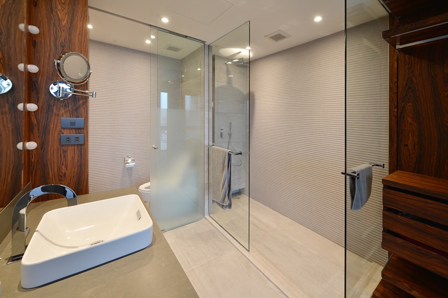 Cuarto de baño elegante con ducha a ras de suelo y mampara fija de vidrio templado, ejemplo visual para entender cómo elegir la mampara de ducha perfecta en baños contemporáneos.